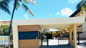 A modern building with a covered entrance, palm trees, and a clear sky. - Marupiara Flat, equipped, free Wi-Fi and parking, best part of the beach (N. São do Ó)