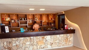 A bar area with a stone wall, shelves with bottles, and a counter. - Marupiara Flat, equipped, free Wi-Fi and parking, best part of the beach (N. São do Ó)