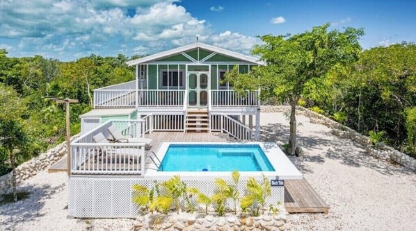 Un bâtiment à deux étages doté d’une piscine, entouré d’arbres et bordé d’une zone sablonneuse.