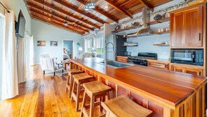 A spacious kitchen with a long wooden island, bar stools, and modern appliances. - Loggerhead - 2BR House at Secret Beach (San Pedro)