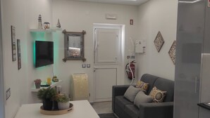 A modern kitchen with a dining area, white cabinetry, a grey sofa, and a small table with chairs. - Light Wave Nazare Center 50m Beach (Nazaré)