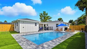 Ein Wohnhaus mit Schwimmbad, überdachter Terrasse und umzäunter Garten.