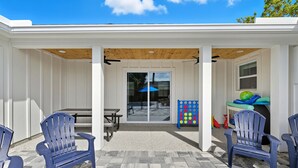 Eine überdachte Terrasse mit Adirondack-Stühlen, einem Tisch und einem bunten Gesellschaftsspiel.