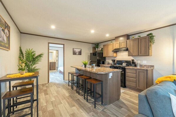 A modern kitchen with a central island, bar stools, and wooden cabinets.