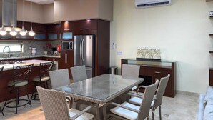 Cozinha moderna com área de jantar, eletrodomésticos de aço inoxidável e um candelabro.