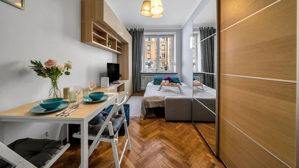 Un espacio habitable compacto con zona de comedor, cama y vista a la ciudad desde una ventana.