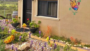 A house with a red roof, a butterfly mural, and a garden with various plants. - Charming fully equipped cottage in Valle de Guadalupe - Early check in! (Ensenada)