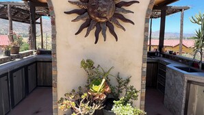 A sun-shaped outdoor kitchen with stone walls and potted plants. - Charming fully equipped cottage in Valle de Guadalupe - Early check in! (Ensenada)