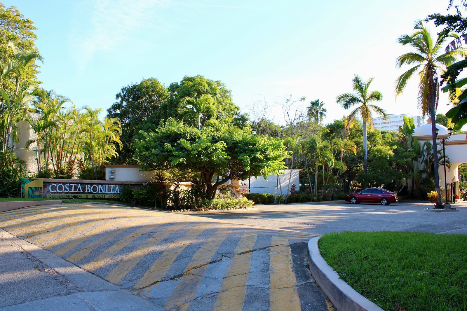 Eine Straße, die zu einem Gebäude führt, an dem ein Schild mit der Aufschrift "Costa Bonita Condominium & Beach Resort" steht.