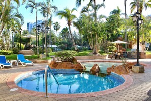 A pool area with lounge chairs, a hot tub, and palm trees. - Costa Bonita Apartments  (Mazatlán)