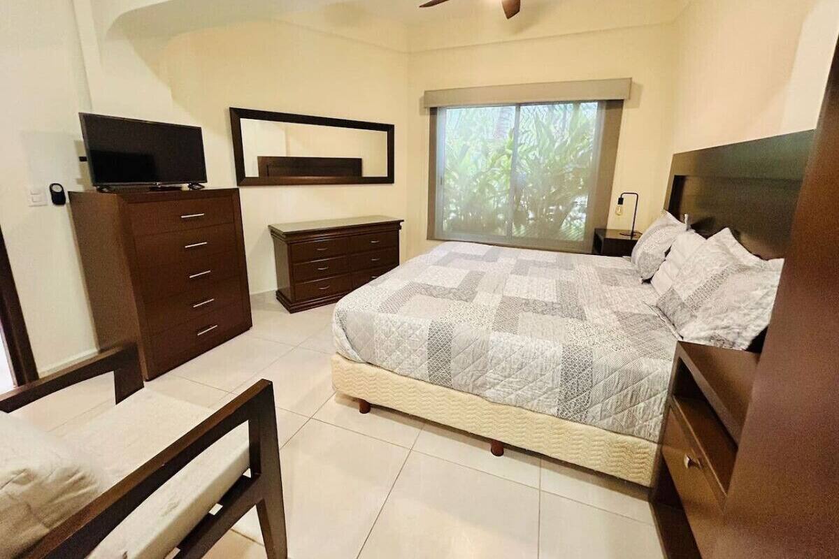 Un dormitorio con cama, escritorio, silla, cómoda y ventilador de techo.