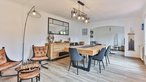 Un'area pranzo moderna con un tavolo e sedie in legno, una scacchiera e un grande specchio a parete.