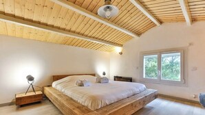 Una camera da letto con un letto di legno, una lampada da comodino e una finestra vista alberi.