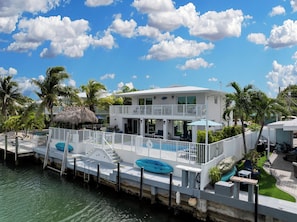 A waterfront property with a pool, a dock, and a two-story building with balconies.