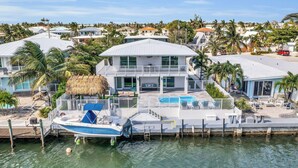 A waterfront property with a large house, a boat docked at the pier, and a swimming pool. - Walk to the Beach, water front, great deal, two for one price, pool, dock, ice. (Key Colony Beach)