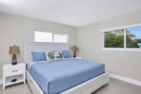 A bedroom with a bed, nightstands, and a window.