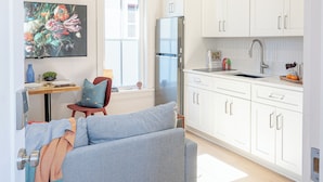 A modern kitchen with white cabinets, a stainless steel refrigerator, and a window.