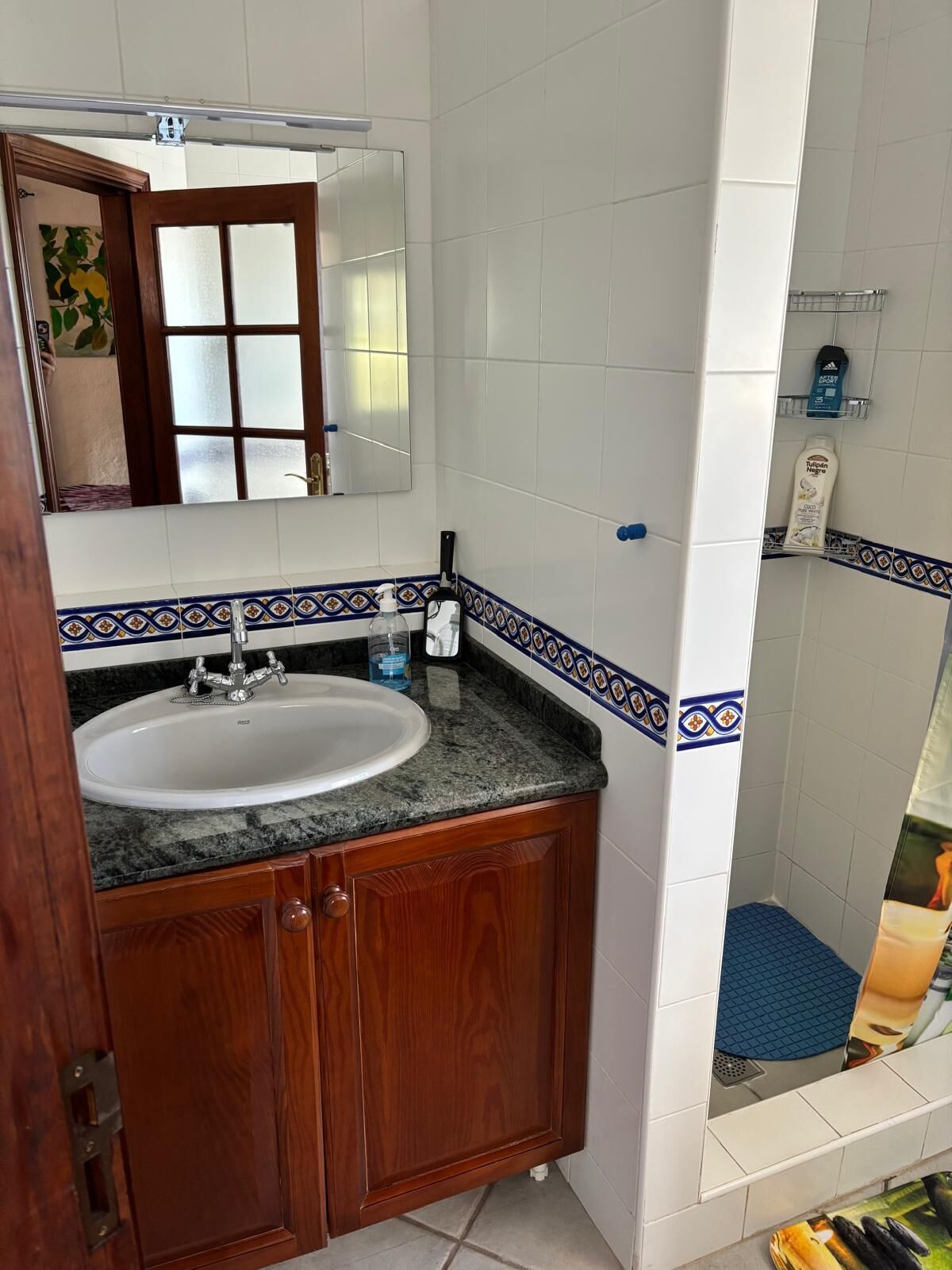 A bathroom with a wooden vanity, a white sink, and a mirror.