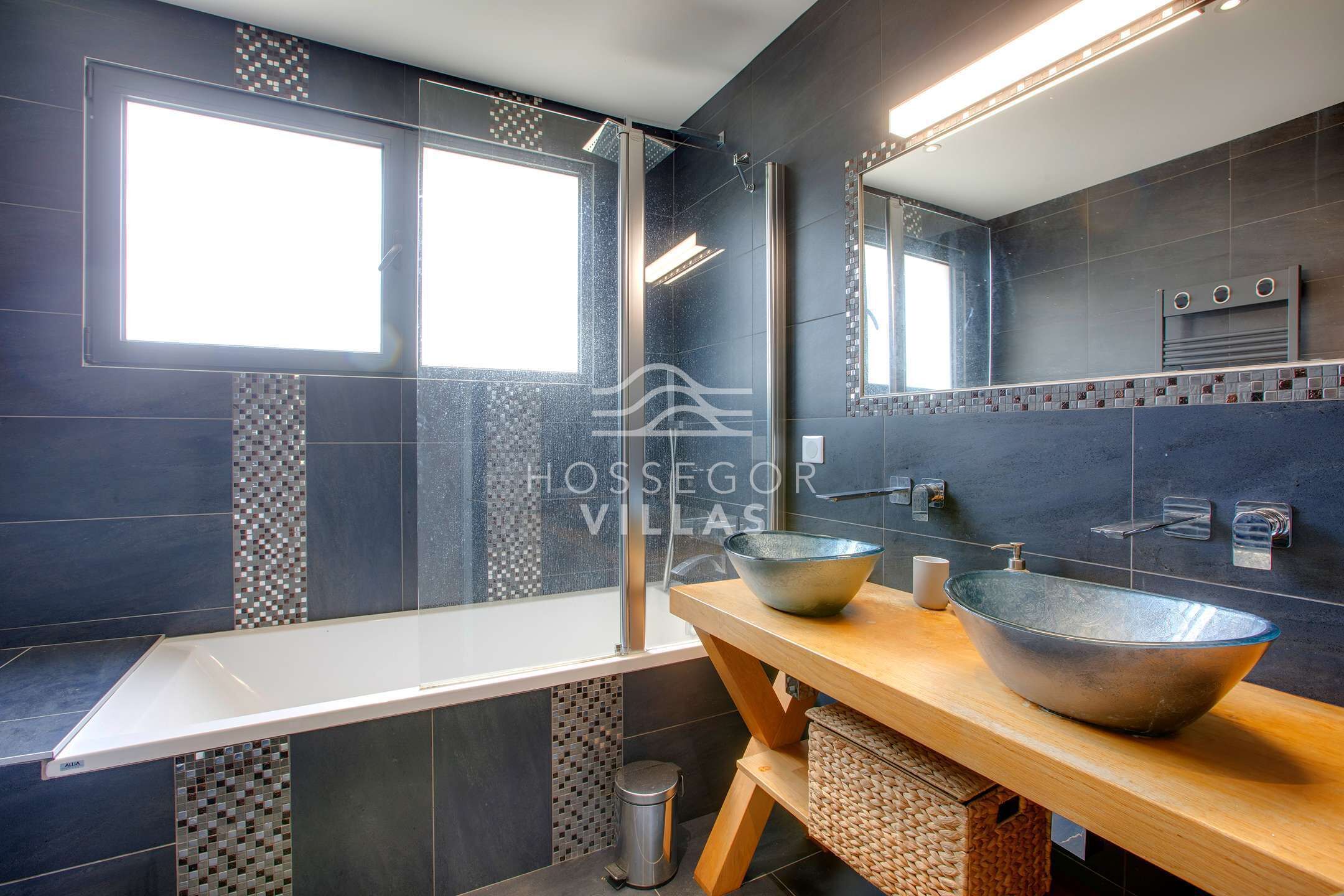 A modern bathroom with a large window, a vessel sink, and a mirror above the sink.