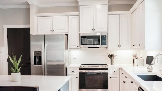 Una cocina moderna con armarios blancos, electrodomésticos de acero inoxidable y suelo de madera.