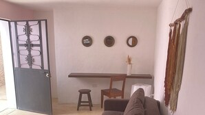 Ett vardagsrum med en soffa, ett litet runt bord, en stol och en matplats med ett bord och stolar.