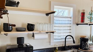 Une cuisine moderne avec un plan de travail noir, des meubles en bois, un lave-vaisselle encastré et une fenêtre agrémentée de rideaux à rayures.