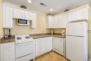 A kitchen with white cabinets, a microwave, a stove, a dishwasher, and a refrigerator.