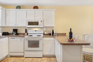 A kitchen with white cabinets, a microwave, a stove, and a coffee maker.
