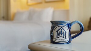 Una taza de cerámica con un logotipo sobre una mesa en una habitación de hotel.