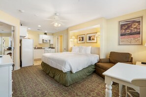 Habitación de hotel con cama, escritorio, silla, kitchenette y baño.