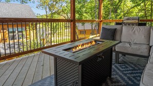 Eine Terrasse im Freien mit Feuerstelle, Grill und Sitzgelegenheit.