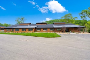 A modern building with a flat roof, large windows, and a paved parking area.