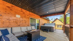 Eine überdachte Terrasse mit Feuerstelle, Sitzgelegenheiten im Freien und Grillbereich.