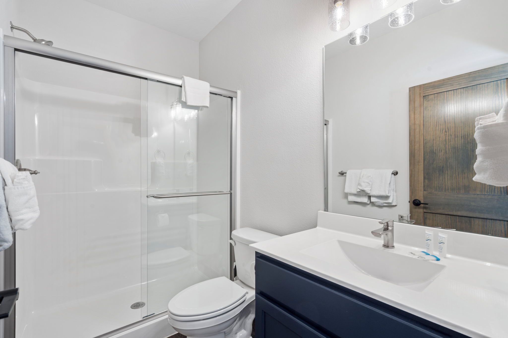 A modern bathroom with a glass shower enclosure, a white toilet, and a vanity with a mirror.