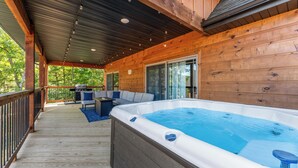 Eine Holzterrasse mit Whirlpool, Gartenmöbeln und einem überdachten Bereich mit Metallveranda.