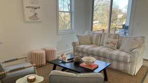 Un salón con un sofá a rayas, una mesita redonda y una silla.