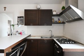 A kitchen with dark wooden cabinets, a white countertop, a gas stove, and a sink.