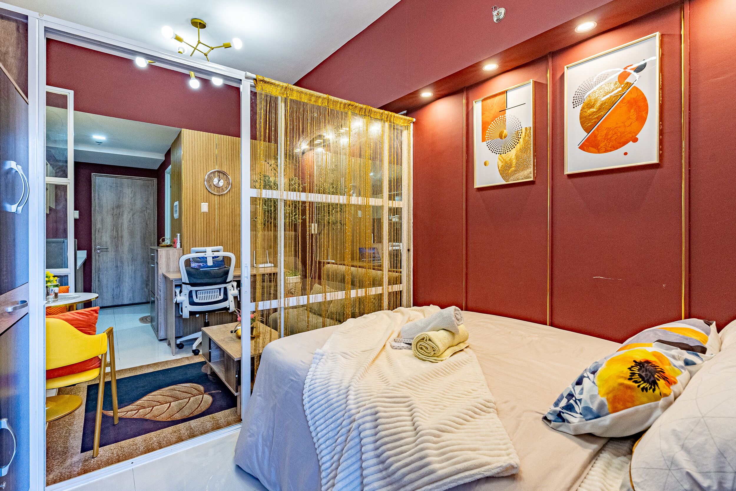A hotel room with a bed, a desk, and a chair. There is a window with curtains and a view of the outside.