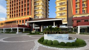 Et moderne hotel med flere etager, en overdækket indgang og en anlagt gårdsplads med velplejede buske.