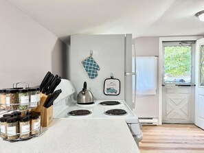 Una cocina con estufa, tetera y especiero.