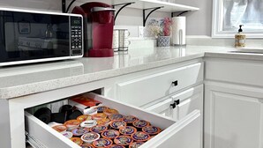 Une cuisine équipée d’un four à micro-ondes, d’une bouilloire rouge et d’un tiroir contenant des boîtes de conservation.