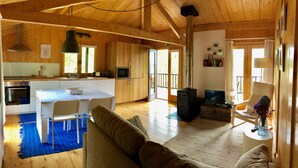 Amplia sala de estar con techo de madera, sofá, televisor y zona de cocina con microondas y estufa.