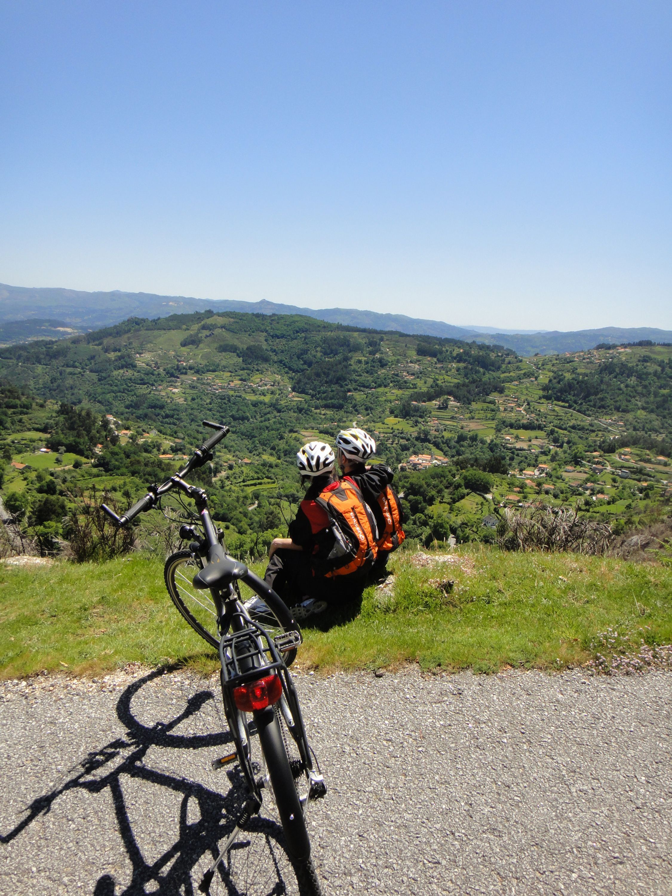 A bicycle parked on a gravel path with a scenic view of green hills and distant mountains.