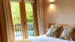 Una habitación de madera con una cama, cortinas y vistas al exterior.