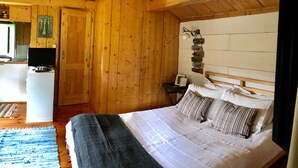 A wooden cabin bedroom with a bed, a desk with a computer, and a wall-mounted sign with motivational phrases. - Pool Villa Espigueiro I (Arcos de Valdevez)