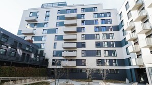 A modern multi-story building with balconies and a courtyard with seating areas. - Fiqus Marcelin Deluxe Apartment (Poznan)