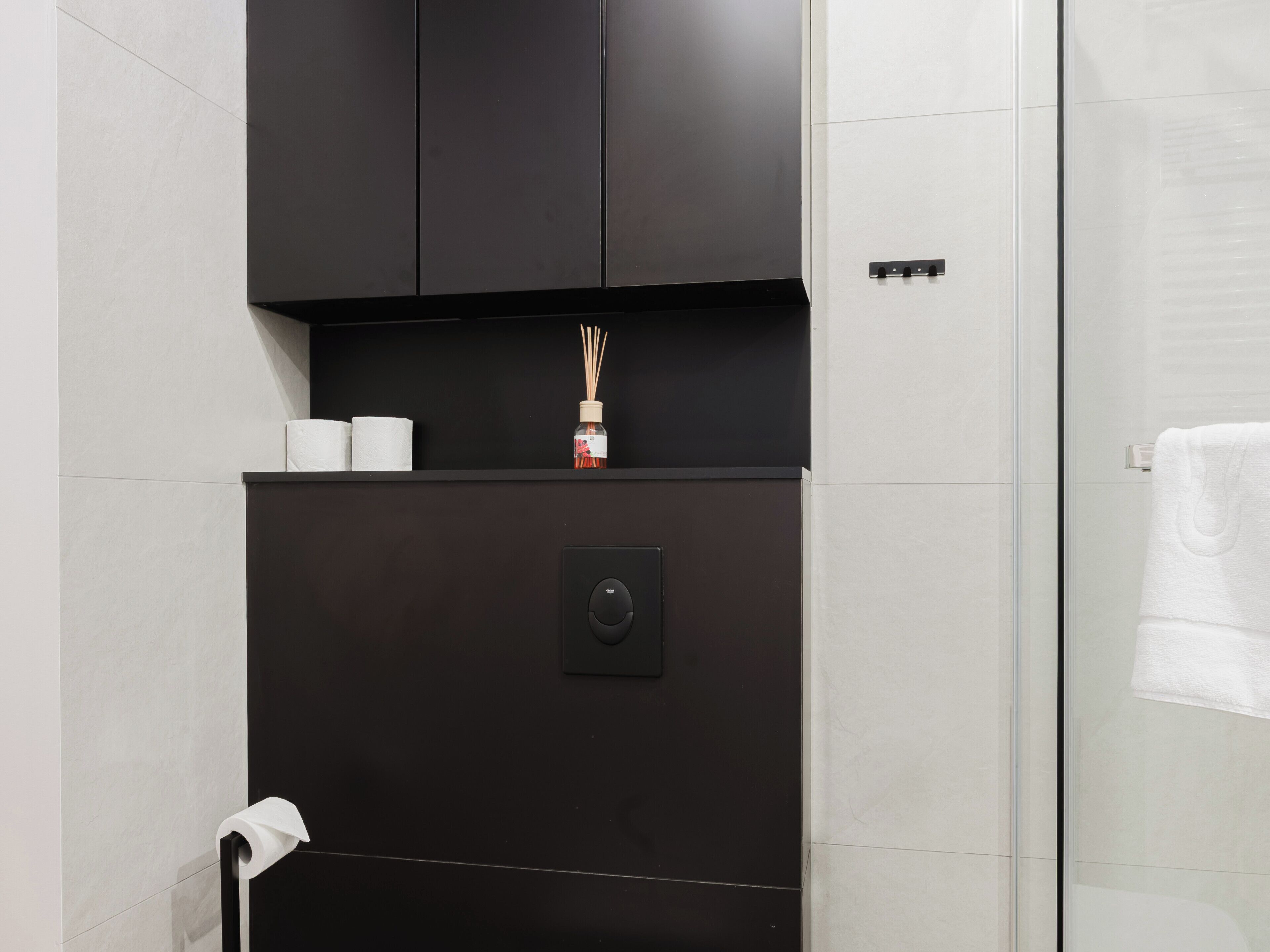 A bathroom with a dark cabinet, a toilet paper holder, and a shower area.