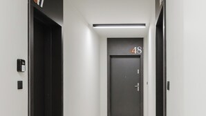 A modern hallway with a door marked '48', a light switch, and a security device on the wall. - Fiqus Marcelin Deluxe Apartment (Poznan)