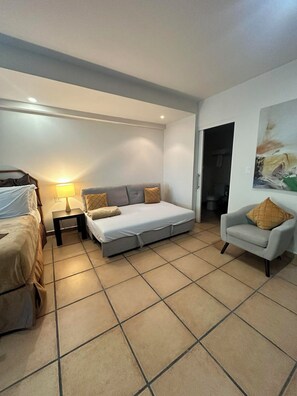 Een hotelkamer met een bed, een sofa, een stoel en een schilderij aan de muur.