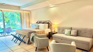 A modern living room with a sofa, armchairs, and a bed. There is a sliding glass door leading to an outdoor area with greenery. - Coronado Luxury Club & Suites - swim up with golf for 2 and resort amenities! (Panamá Oeste Province)